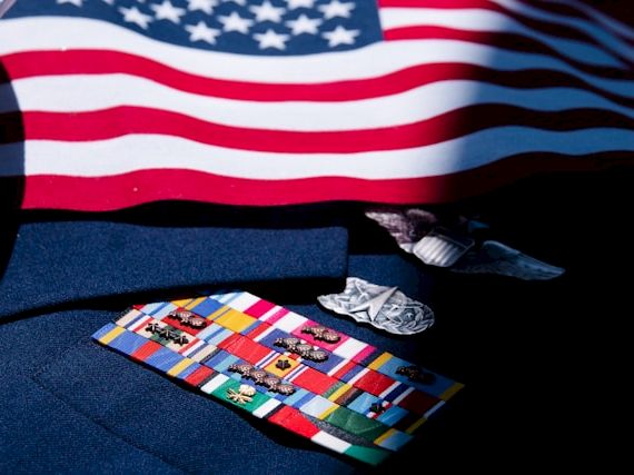 An American flag drapes over a table beside folded money, a necktie, and small cards.